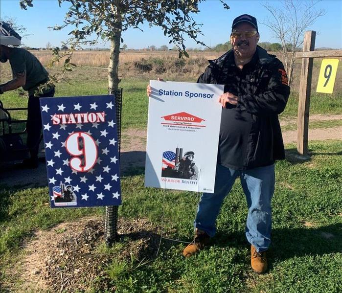 Man standing next to tree with two signs in the ground. 